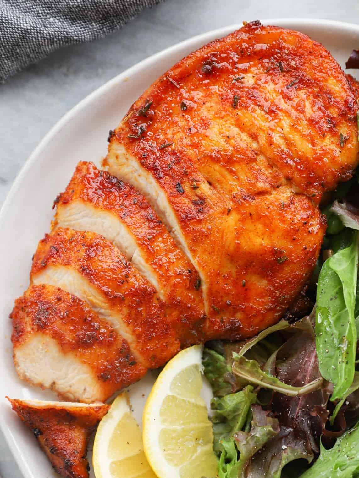 sliced chicken breast on a white plate with salad