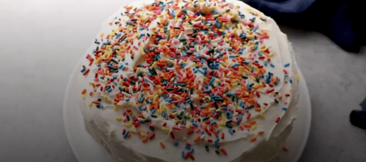 Cake covered with white icing and colored sprinkles. 
