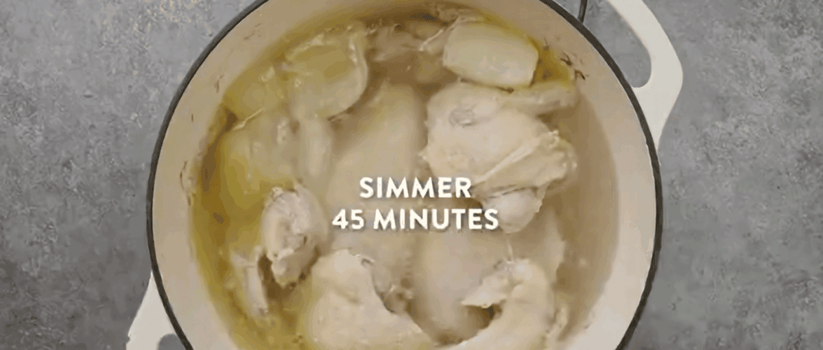 Chicken pieces in a pot with garlic and onion all covered in water. 