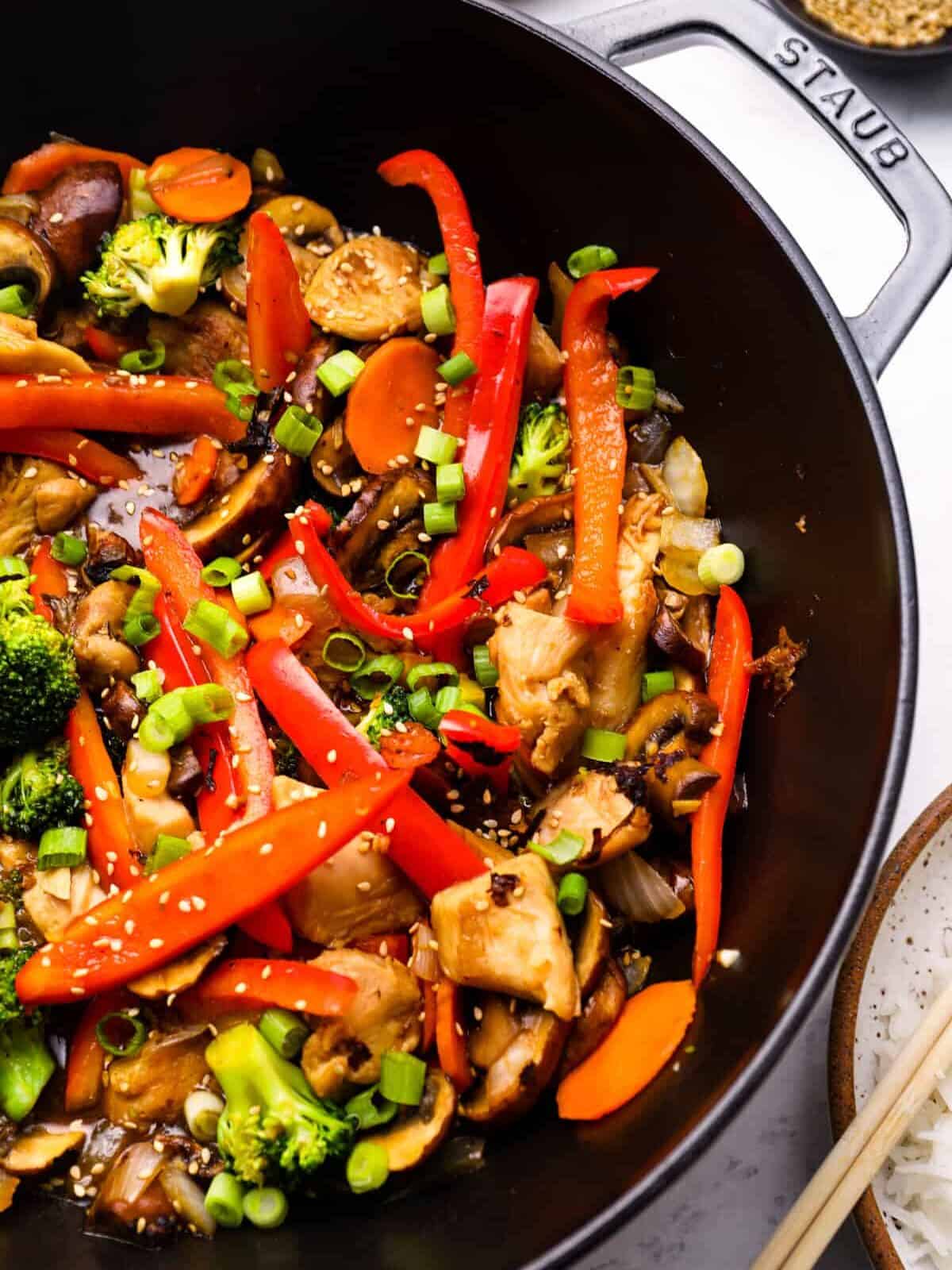 close up view of chicken stir fry in a cast iron wok.