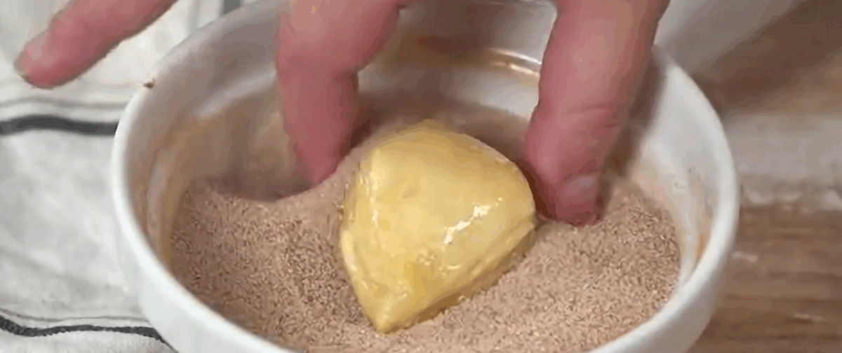 Dipping a butter-drenched cinnamon sugar bite in cinnamon sugar mixture. 