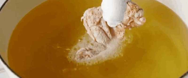 Dropping a chicken wing into hot oil.