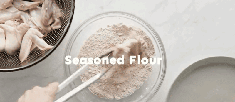 Dredging the chicken wings in the flour mixture.