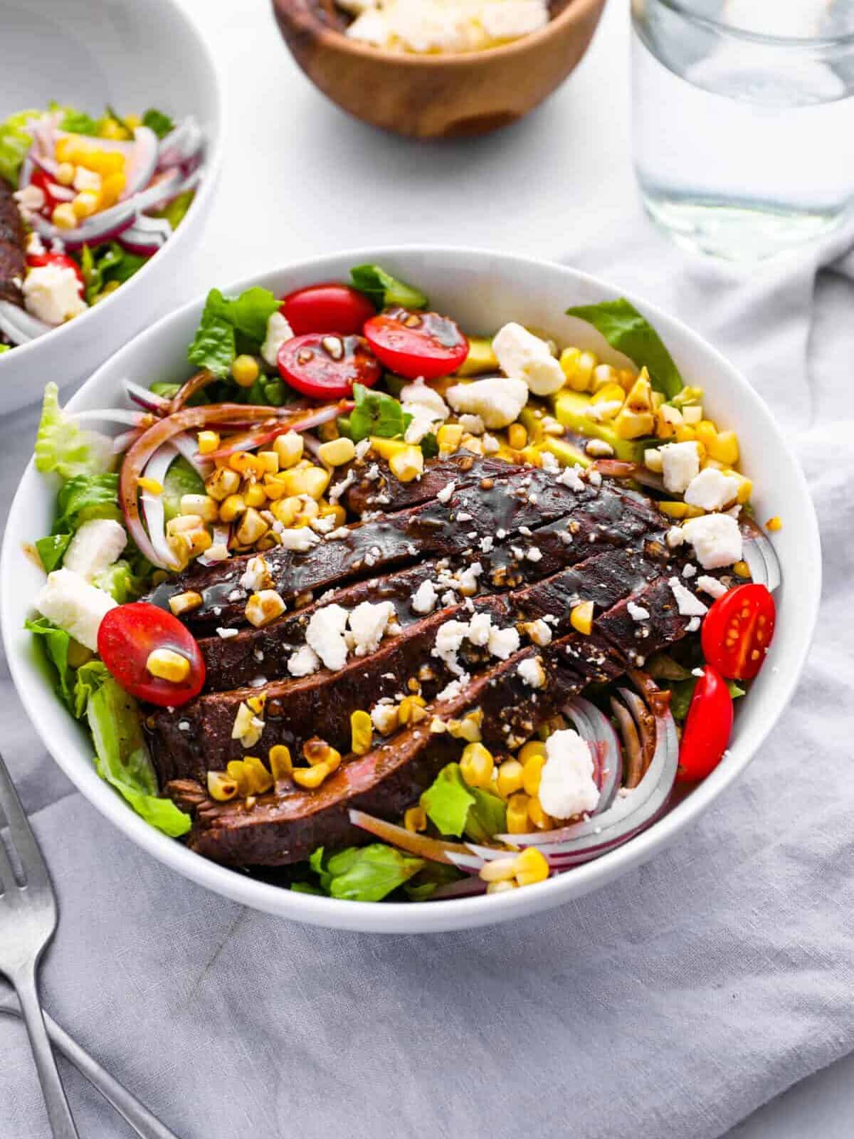steak salad with homemade dressing in a white bowl.