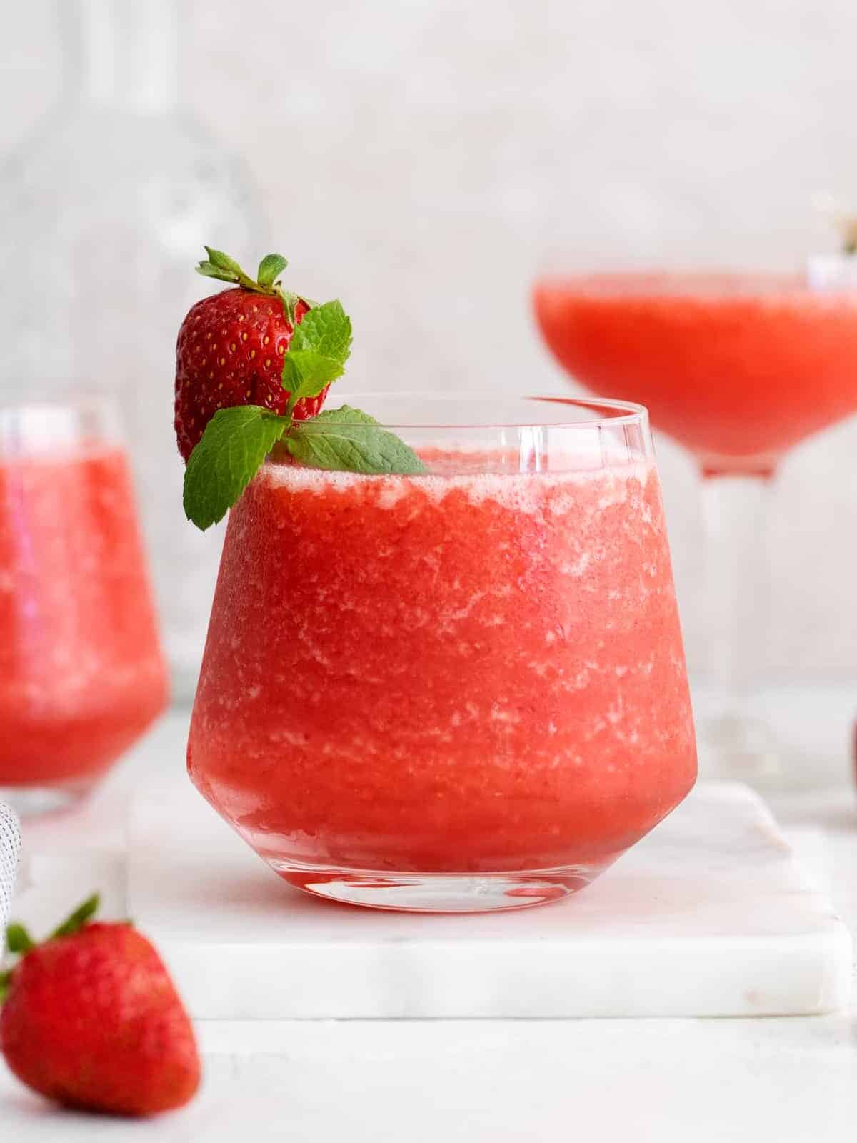 a glass of strawberry frose, garnished with a fresh strawberry