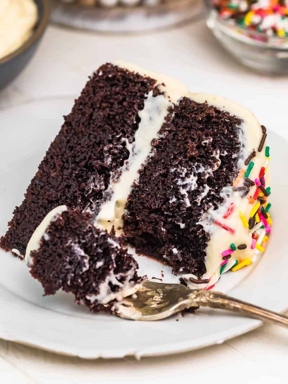 A piece of chocolate cake on a plate, with Icing and fork