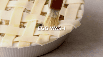 egg washing a lattice pie crust with a pastry brush.