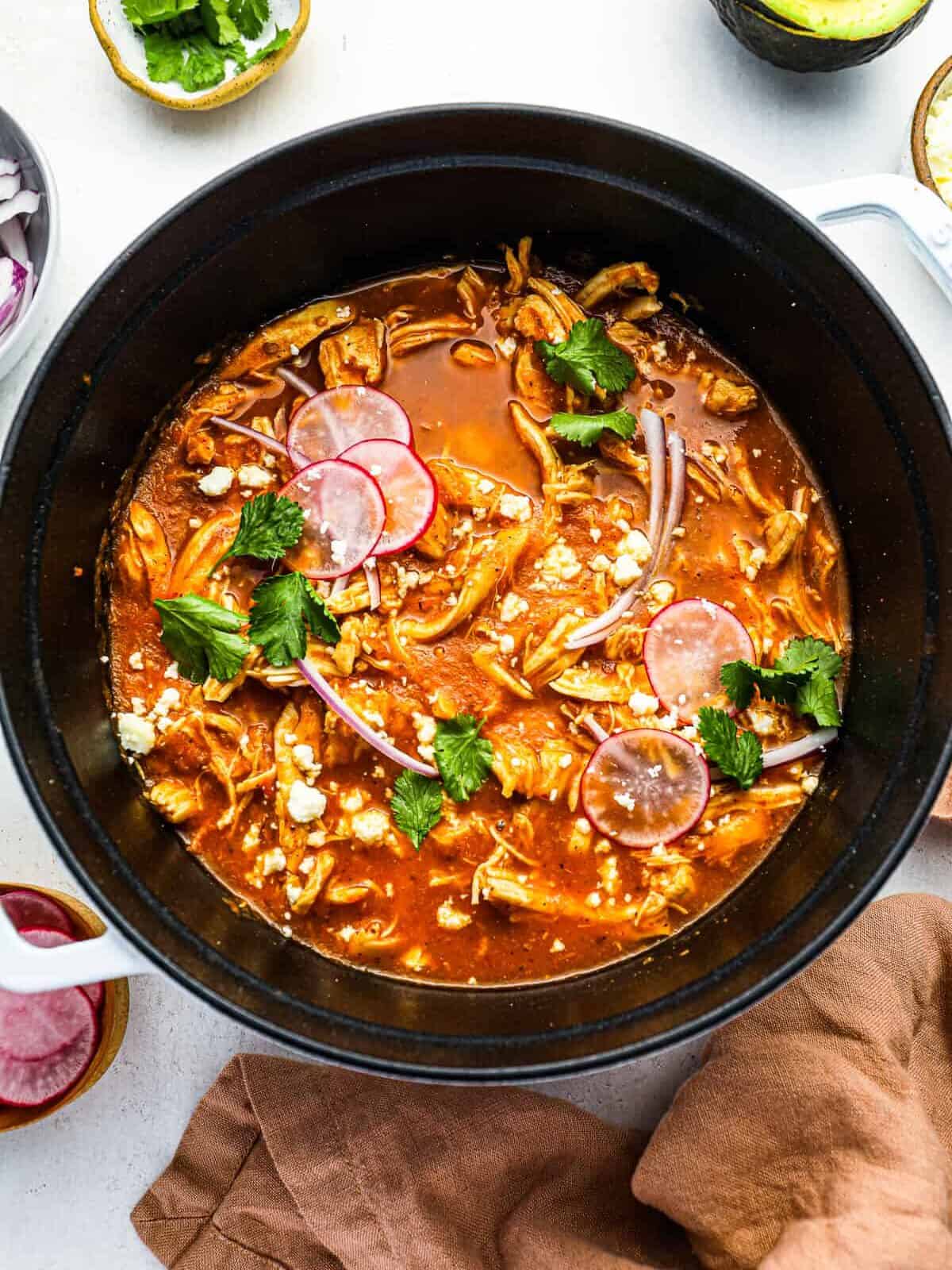 overhead view of chicken tinga in a white and black dutch oven.