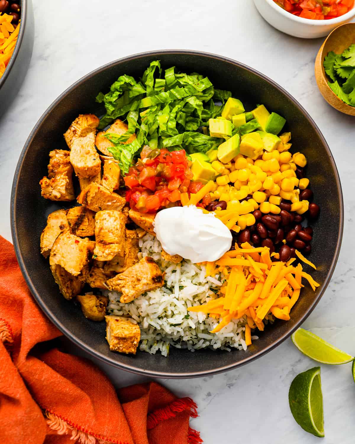 a burrito bowl with copycat Chipotle chicken, rice, corn, beans and sour cream.