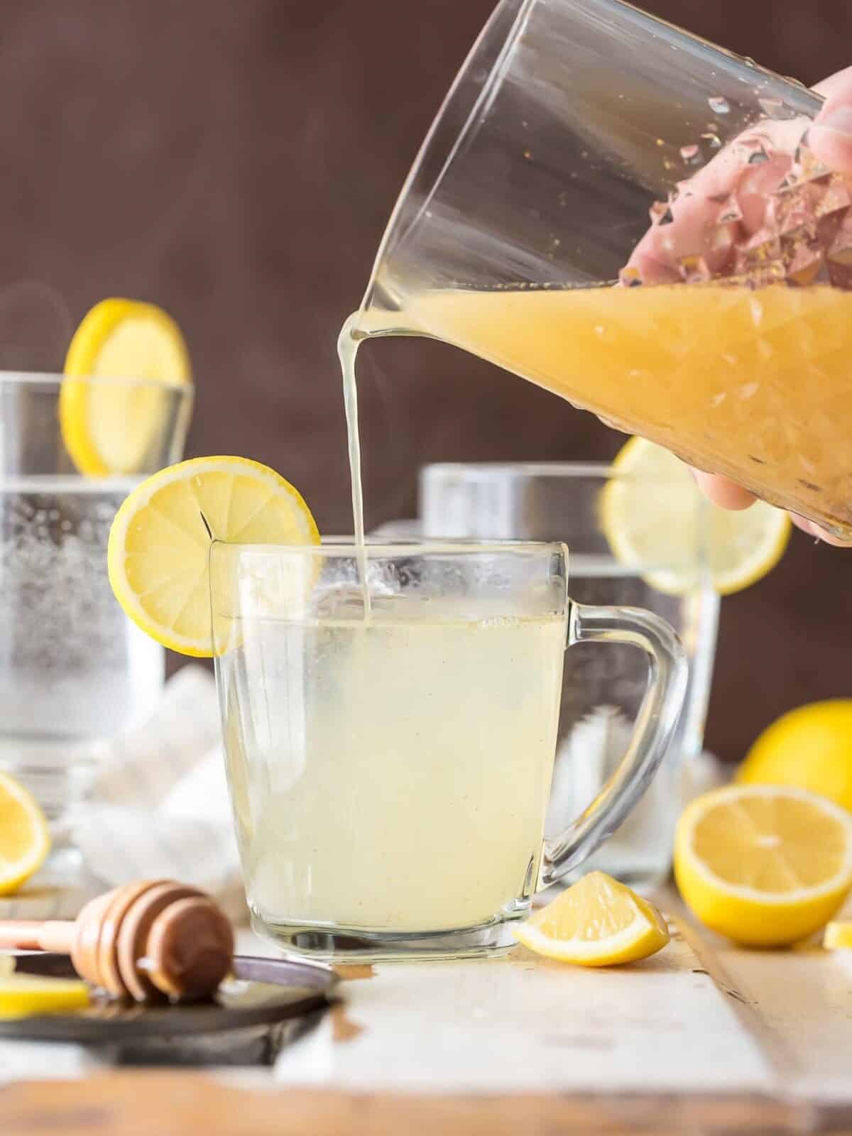 pouring lemonade cleanse from a pitcher into a glass mug.