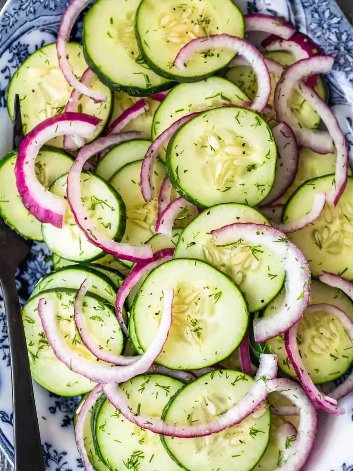 fresh cucumber and red onion salad sprinkled with dill, on a serving plate