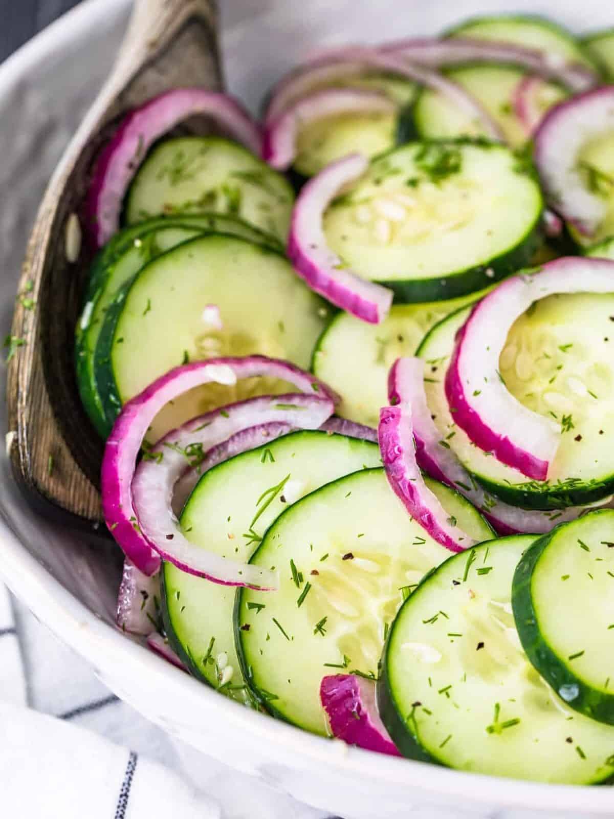close up on cucumber onion salad in a white bowl