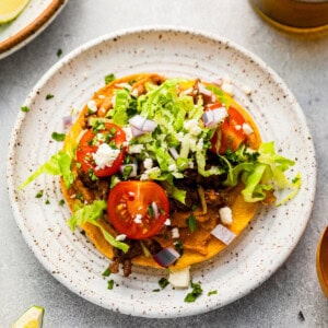 mexican tostadas on a plate with tomatoes and lettuce.