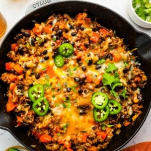 a skillet full of tacos with cheese and black beans.