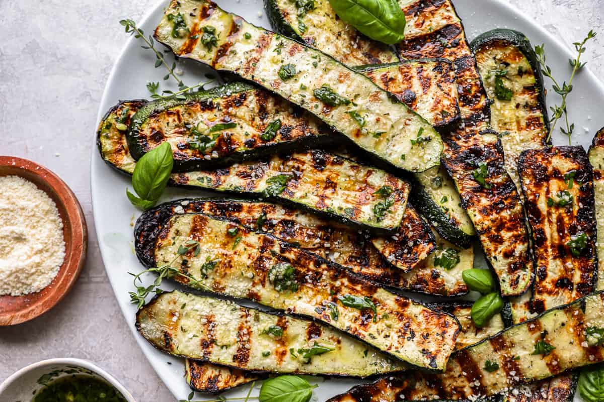 grilled zucchini piled onto on a white oval serving plate.