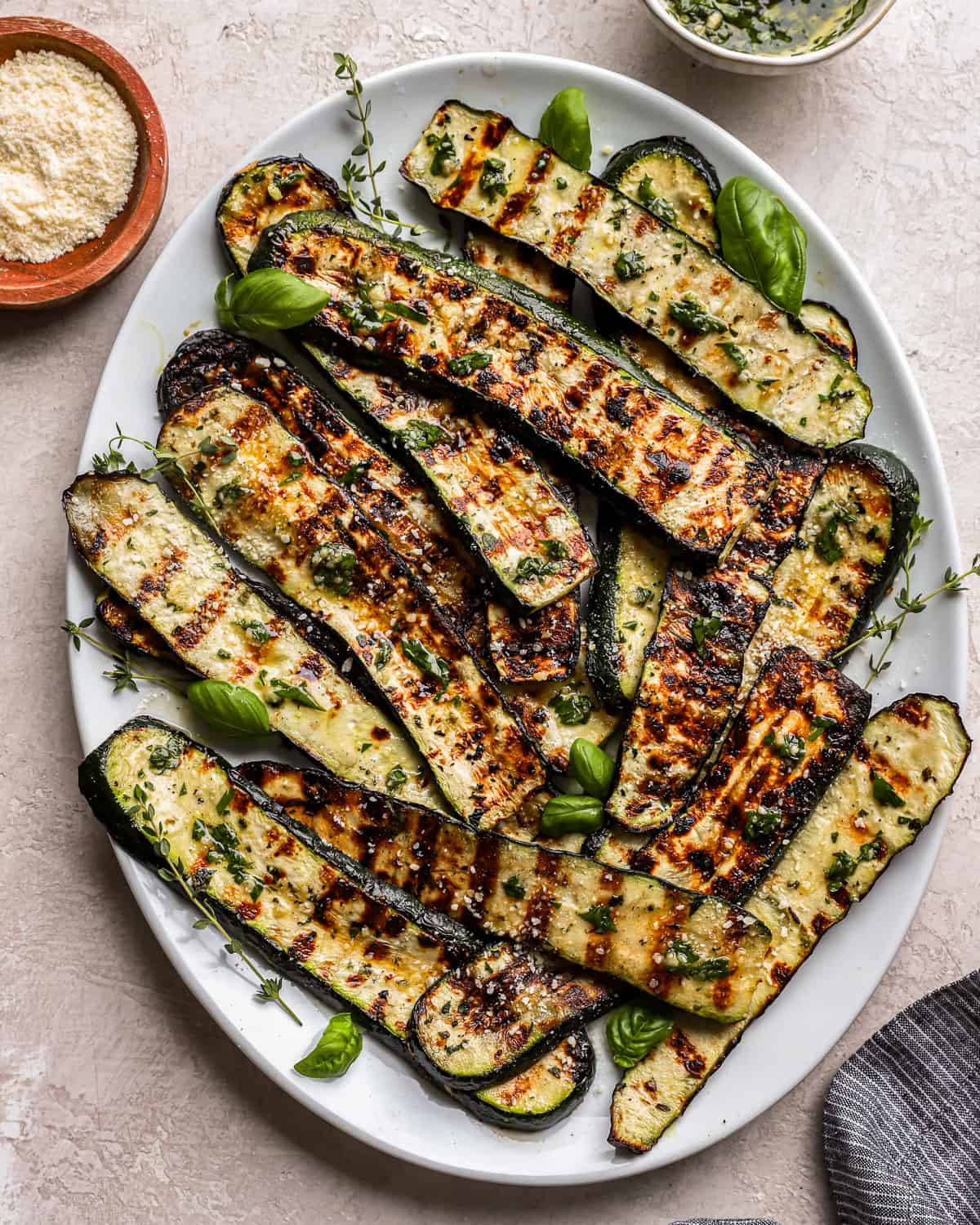 overhead view of grilled zucchini on a white oval plate.