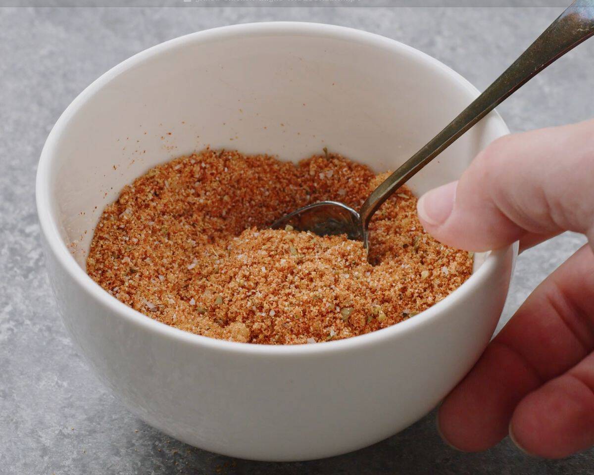 Homemade chicken thigh seasoning made with brown sugar and spices being mixed in a small white bowl.