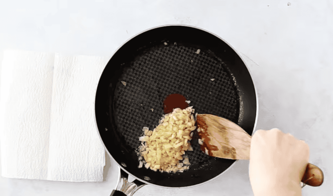 Sauteeing onions in a black pan.