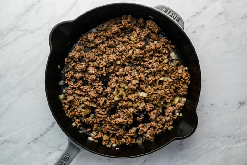 a skillet filled with ground beef and onions.