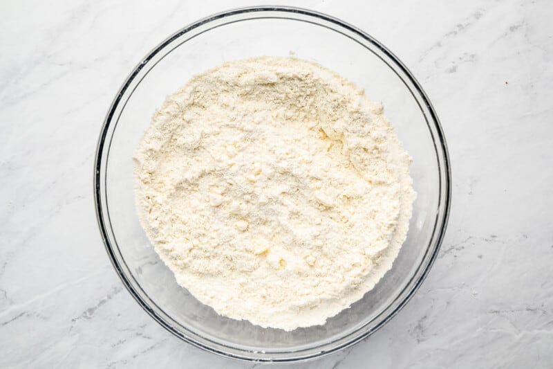 flour in a glass bowl on a marble countertop.