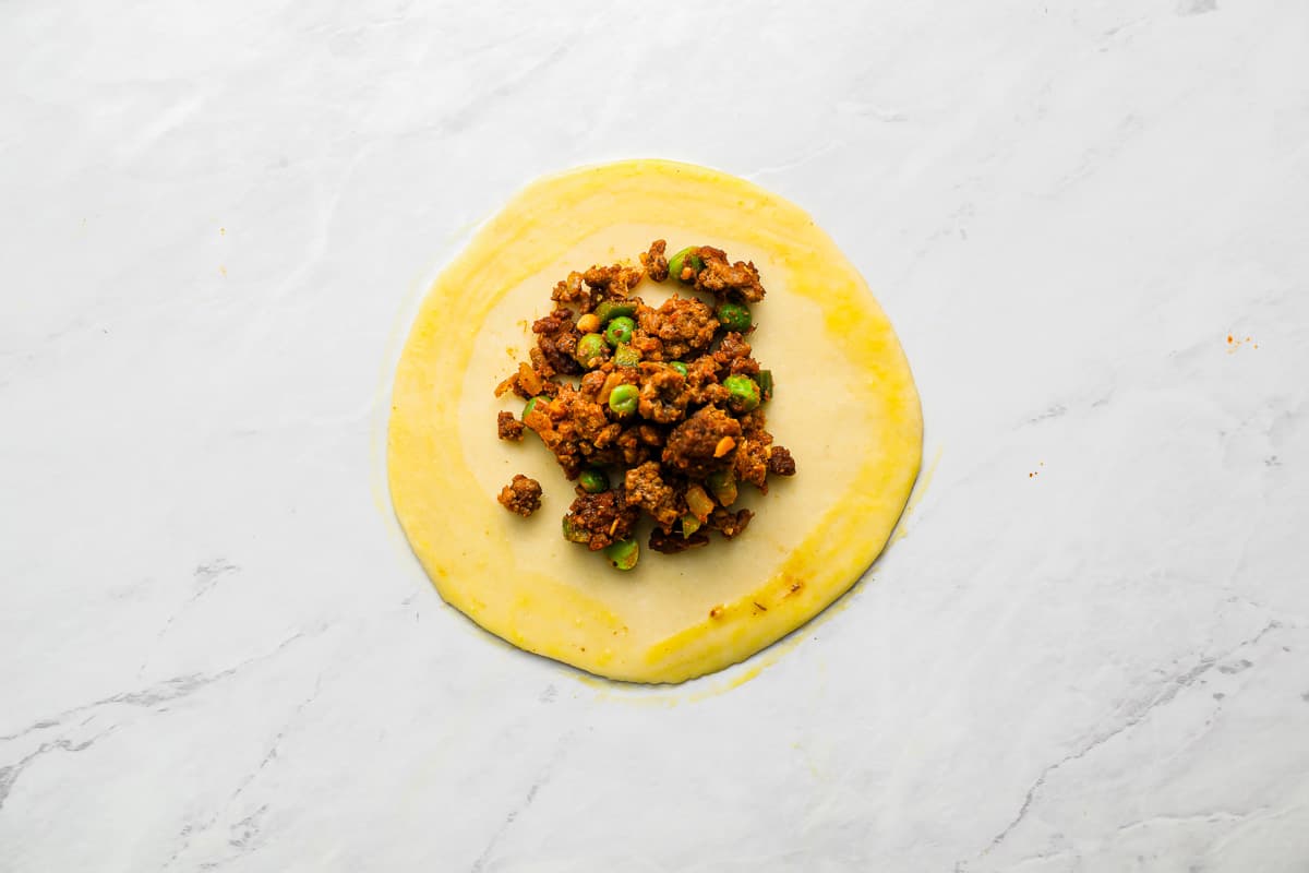 a dish with meat and peas on top of a white surface.