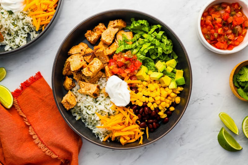 a bowl of mexican food with sour cream, guacamole and tortilla chips.