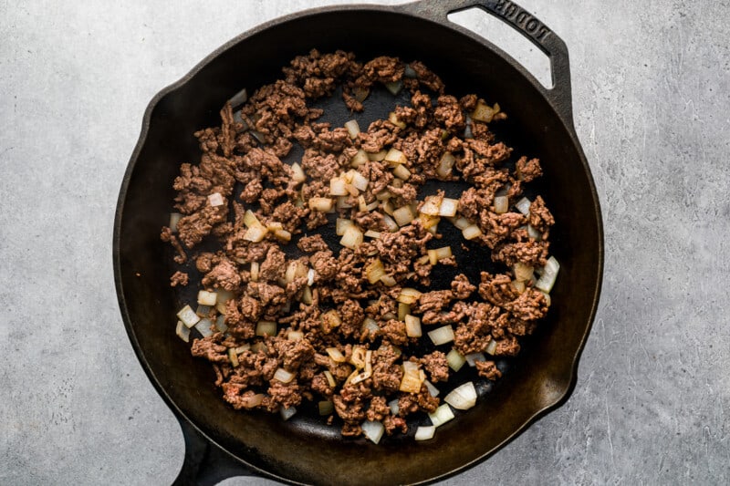 a cast iron skillet filled with ground beef and onions.