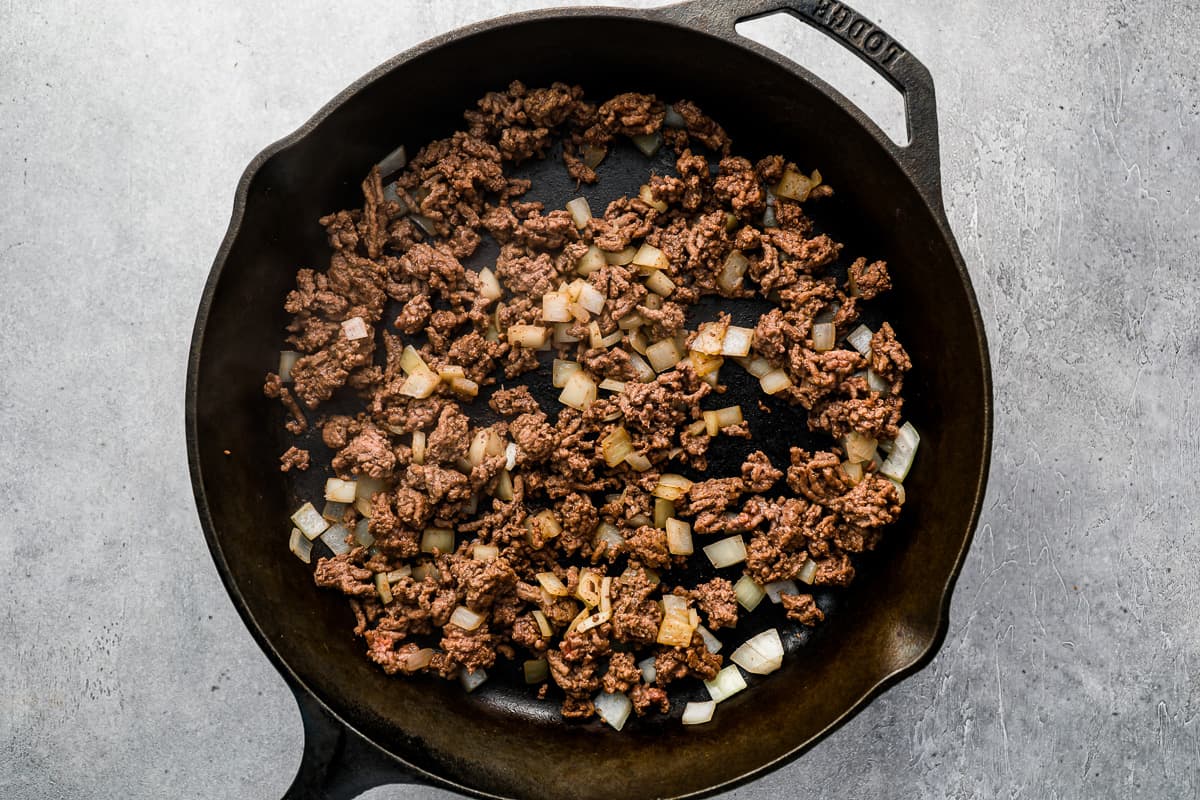 a cast iron skillet filled with ground beef and onions.