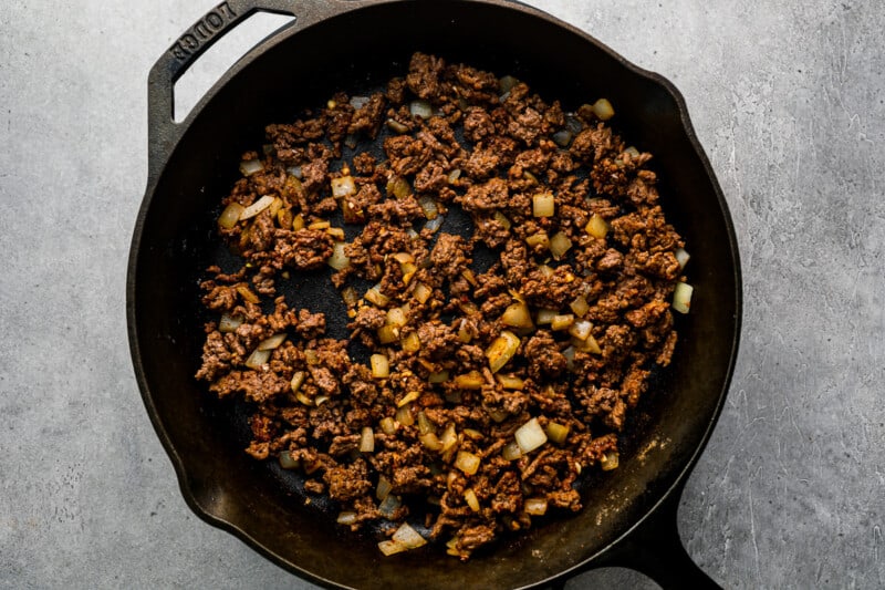 a skillet filled with ground beef and onions.
