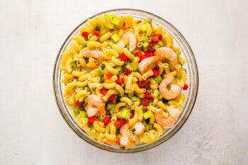 overhead view of ingredients for shrimp pasta salad in a glass bowl.