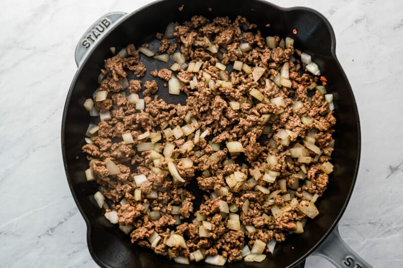a skillet filled with ground beef and onions.