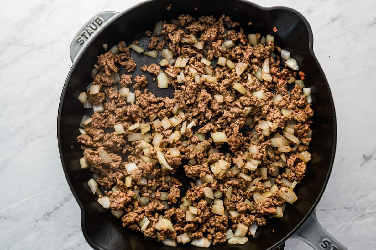 a skillet filled with ground beef and onions.