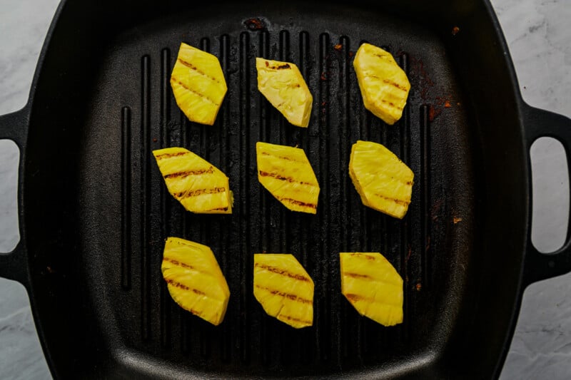 grilled pineapple slices in a cast iron pan.
