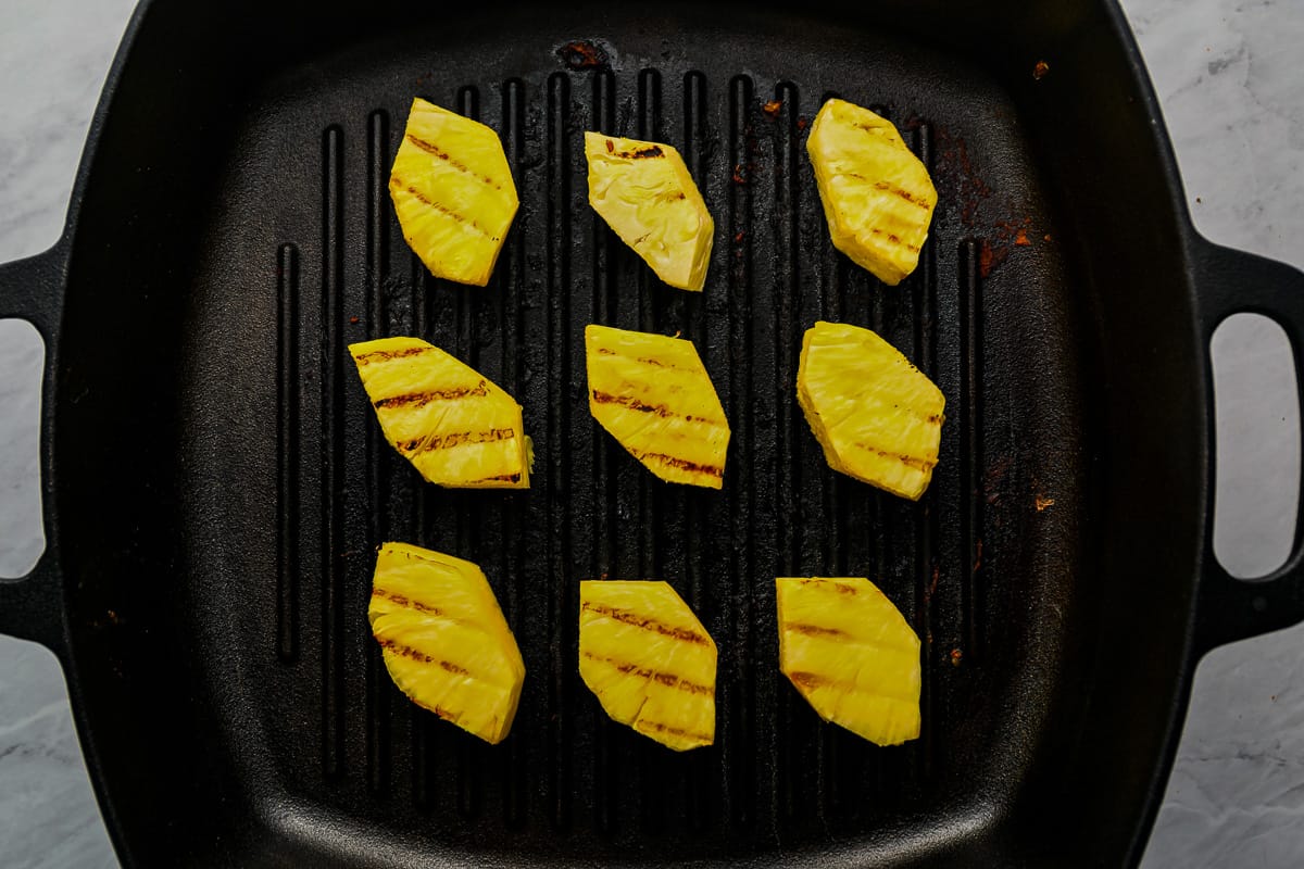 large chunks of pineapple cooking in a grill pan.