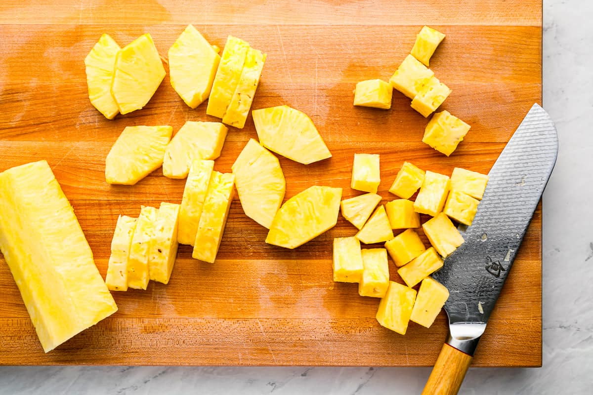 sliced pineapple on a cutting board with a knife.