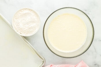 milk added to wet ingredients for vanilla cake in a glass bowl.