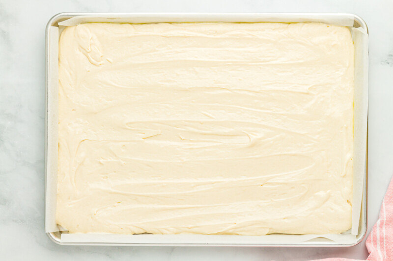 vanilla cake batter spread out in a sheet cake pan.