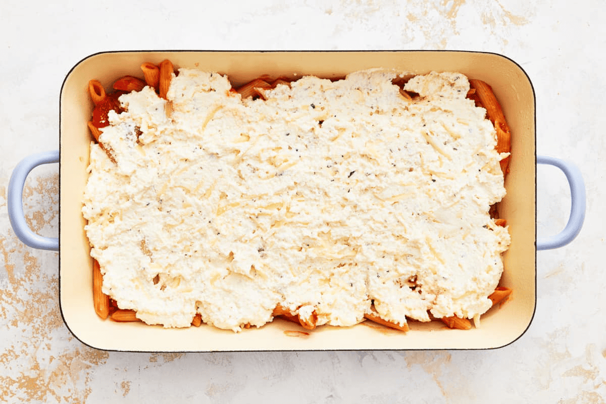 Spreading the cheese mixture over the pasta and sauce. 