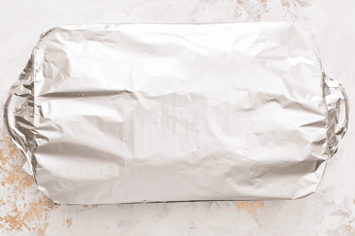 Covering the baking dish with aluminum foil.