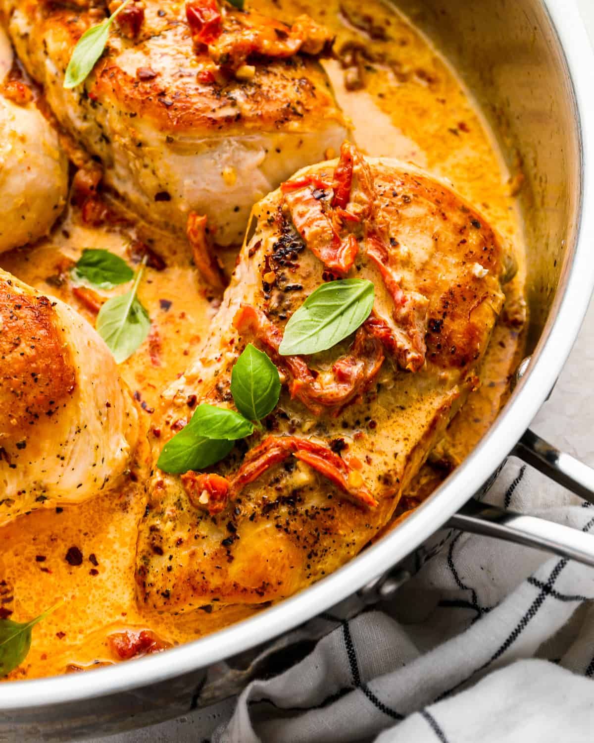 close-up three-quarters view of marry me chicken in a stainless pan.