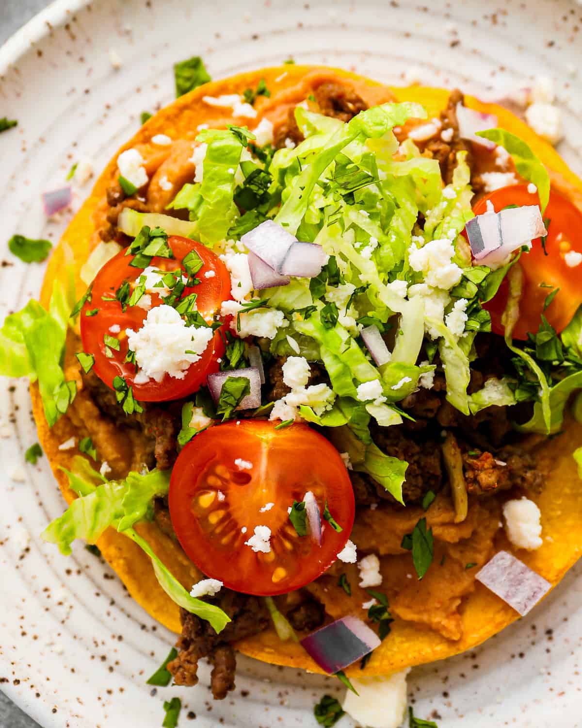 mexican tostadas on a plate with tomatoes and lettuce.