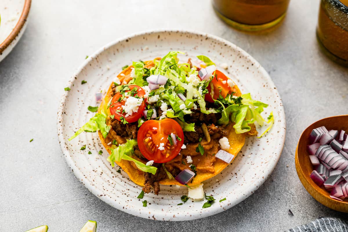 mexican tostadas on a plate next to a glass of beer.