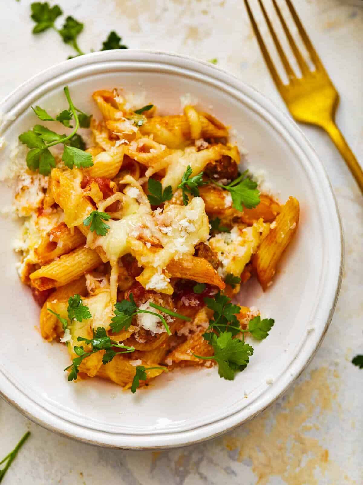 a plate of mostaccioli next to a fork