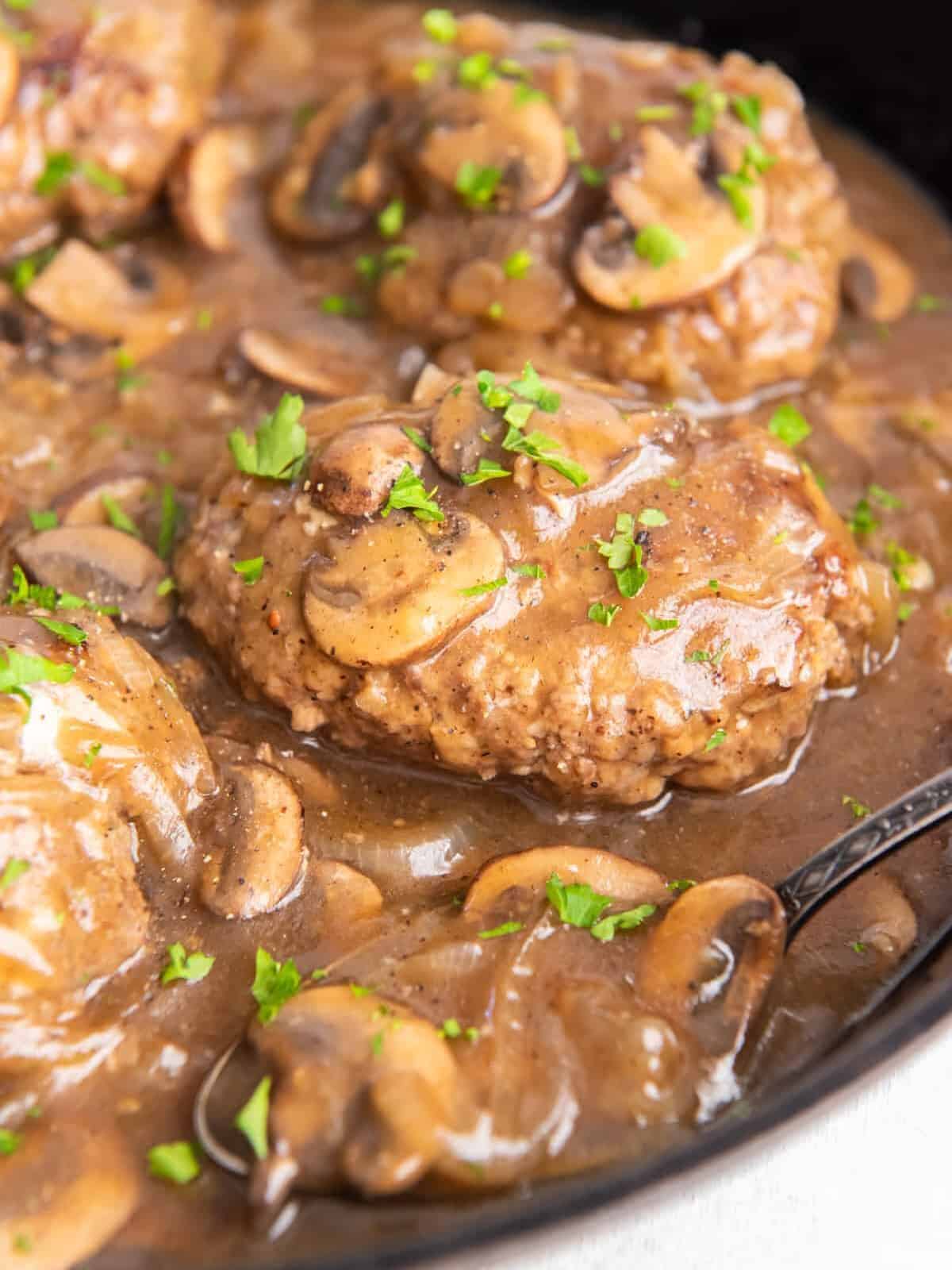 close up of salisbury steaks in a cast iron pan.