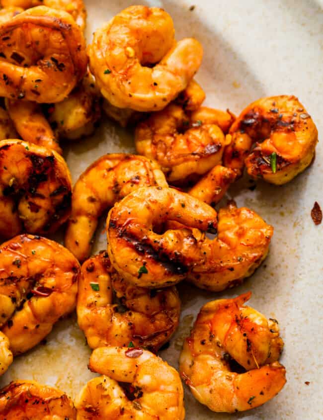 close-up overhead view of marinated grilled shrimp on a white plate.