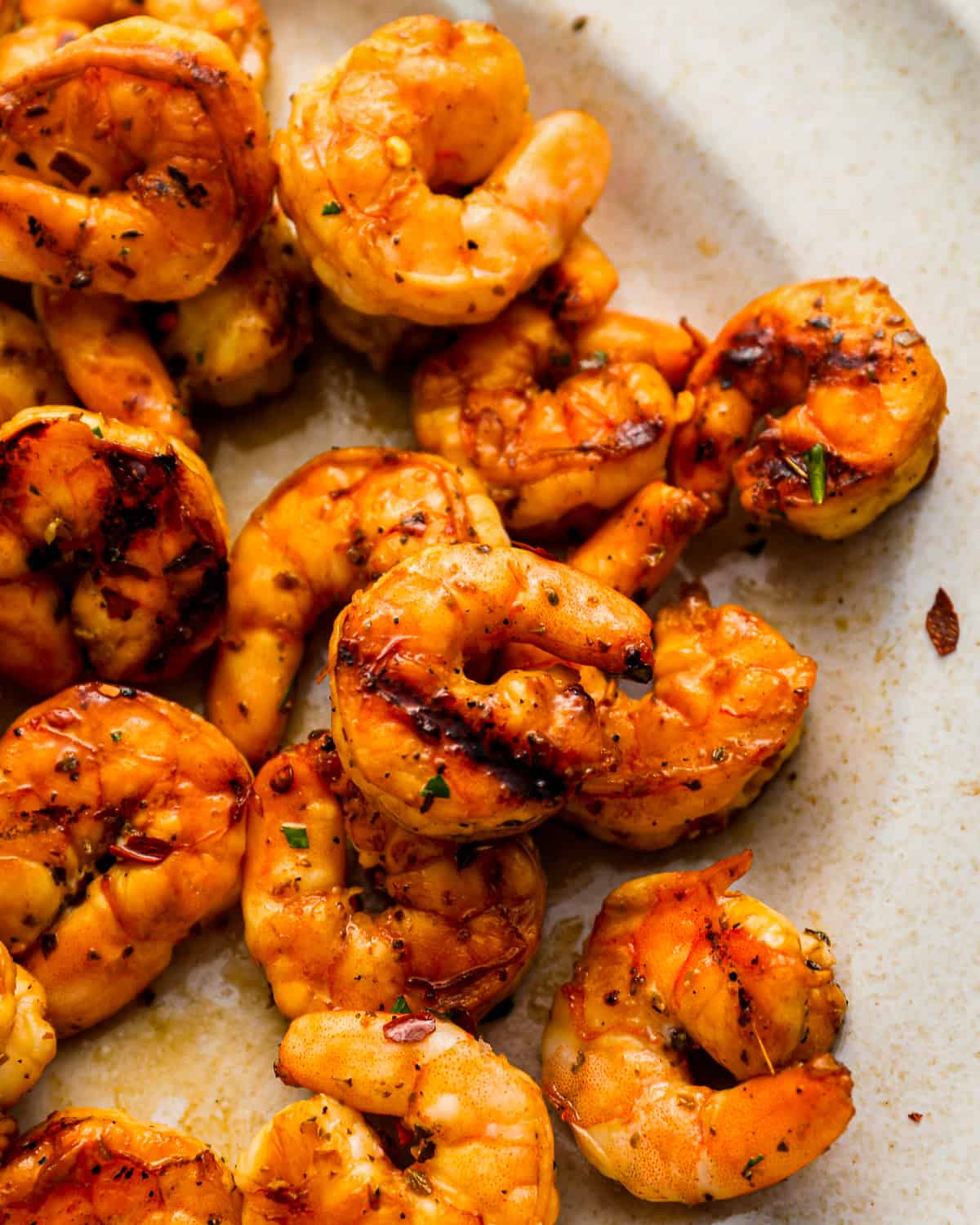 close-up overhead view of marinated grilled shrimp on a white plate.