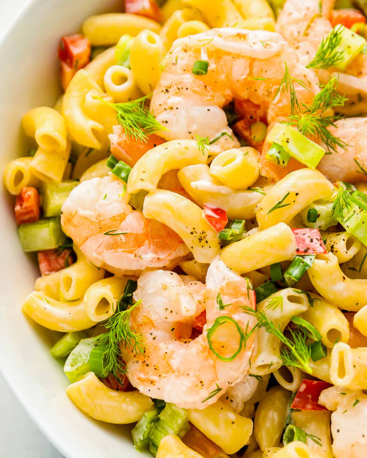 close up view of shrimp pasta salad in a white bowl.