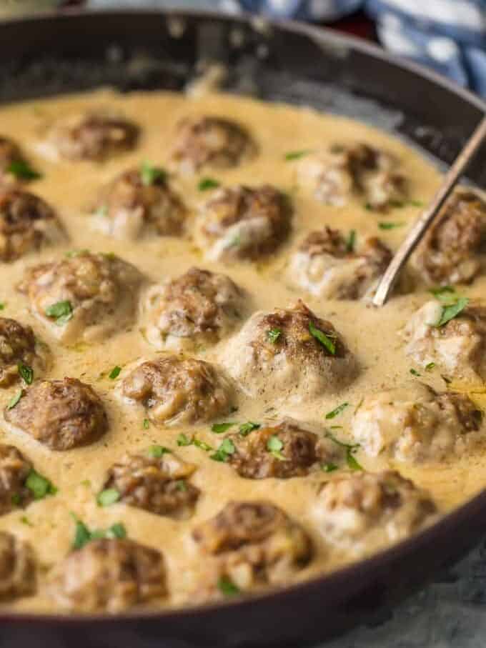 close up on Swedish meatballs cooking in a creamy sauce in a skillet