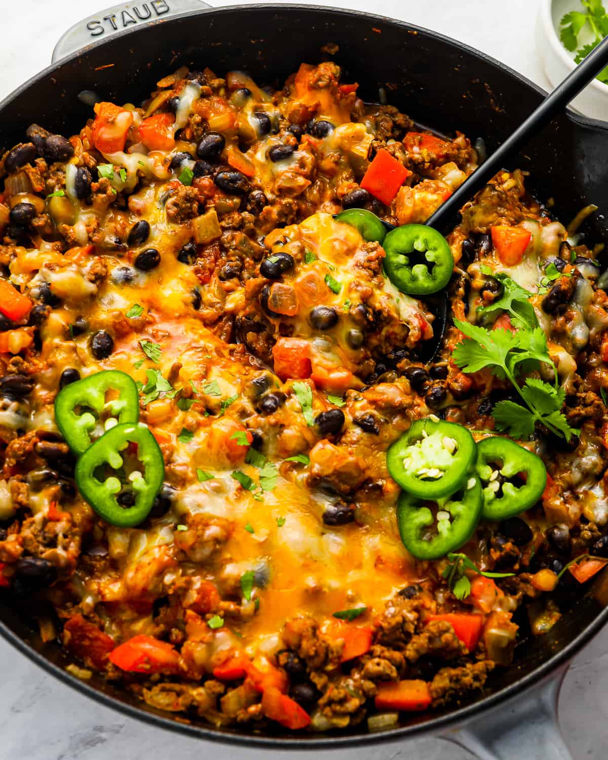 a skillet full of cheesy mexican rice with black beans and peppers.