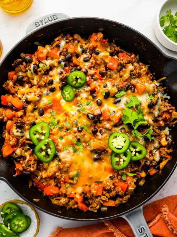 a skillet full of cheesy mexican rice with black beans and jalapenos.
